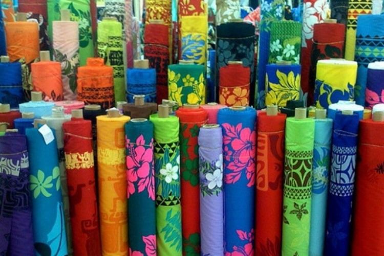 More than 60 rolls of colorfull Hawaiian print fabrics standing upright.